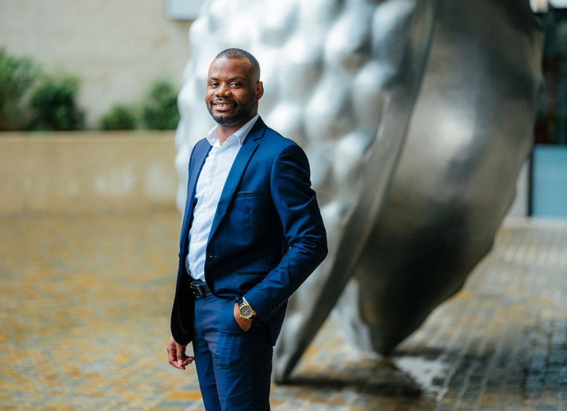 Smiling man in suit standing in office lobby.