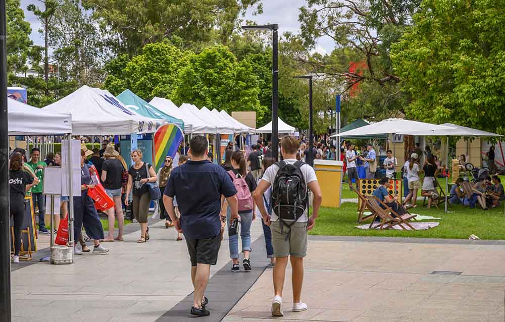 An outdoor view of trees, tents and crowds at Kelvin Grove campus