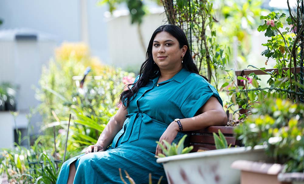A woman in a green dress sitting on a park bench.