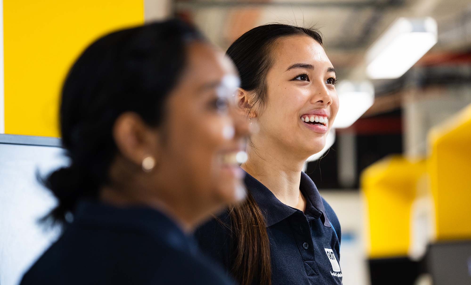 Two female students smile as they listen to a joke told by a medical imaging academic.