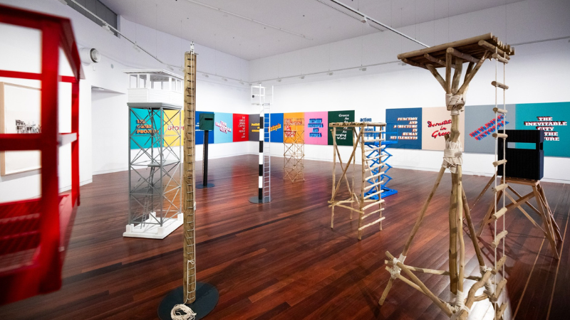 a selection of different statues made out of wood sit in a room with wite walls and colourful quotes stuck on the wall