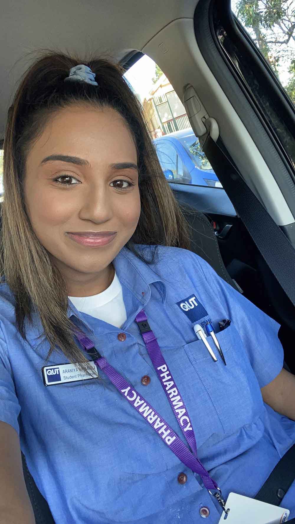 Female student in pharmacy uniform sits in the car ready to start a shift in a clinic.