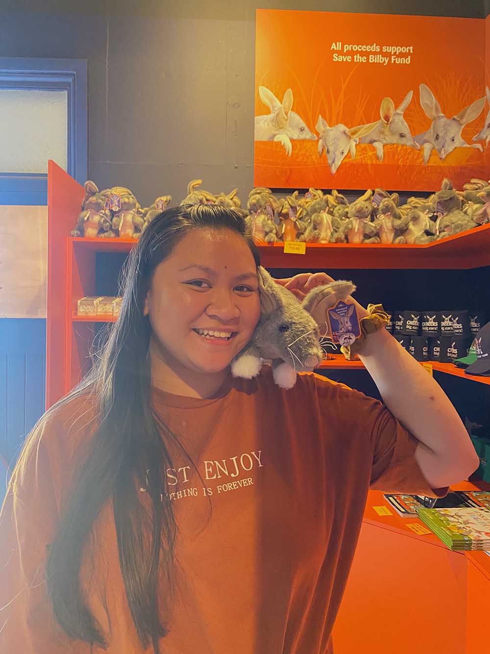 A female student holds a toy bilby in a tourist gift shop.