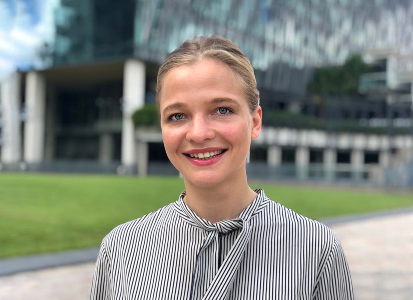 QUT student Adriana standing on campus smiling towards the camera