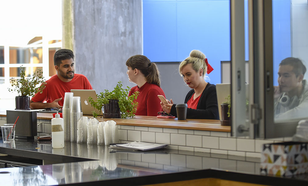 A group of postgraduate students talk while sitting together at a coffee shop, they are waiting to go in to a lecture.