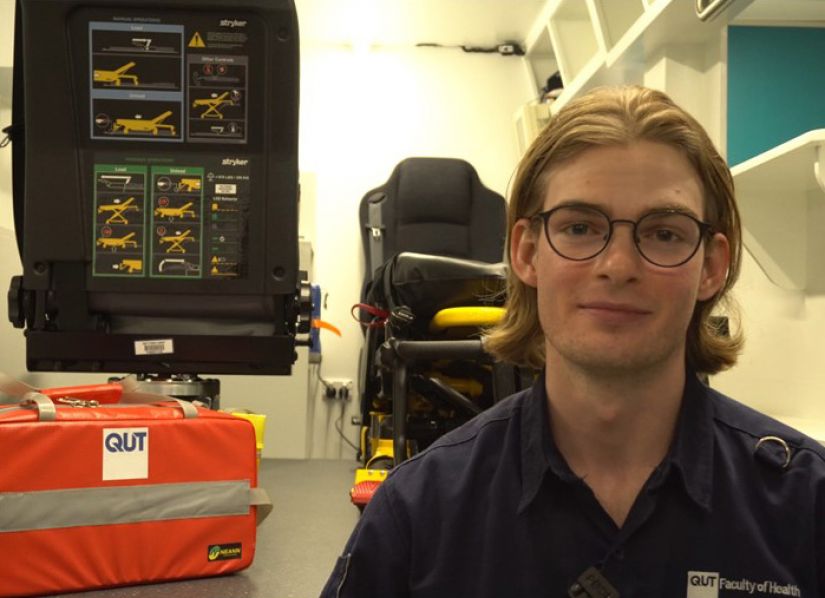 Student in paramedic science uniform sits in ambulance simulation equipment