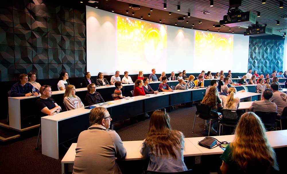 A group of students sit in a modern lecture theatre.