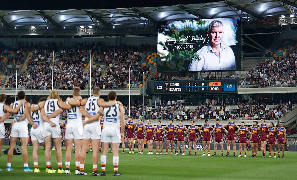 In a large stadium players and fans observe a minute of silence for footballer and coach Danny Frawley who suffered from chronic traumatic encephalopathy.