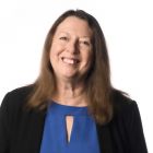 A portrait of a white woman with shoulder-length brown hair.