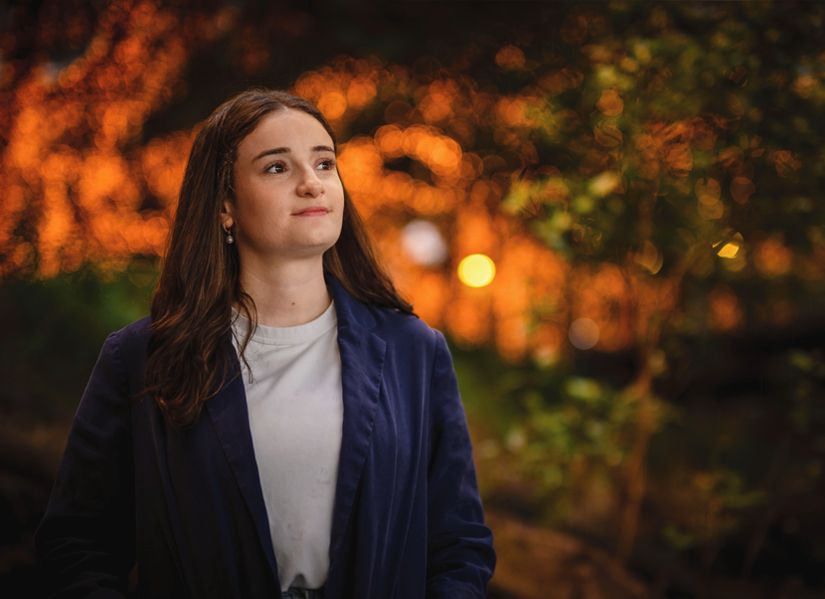 Zoe Zollinger standing amongst the mangroves at the QUT Gardens Points campus at dusk with a warm light around her