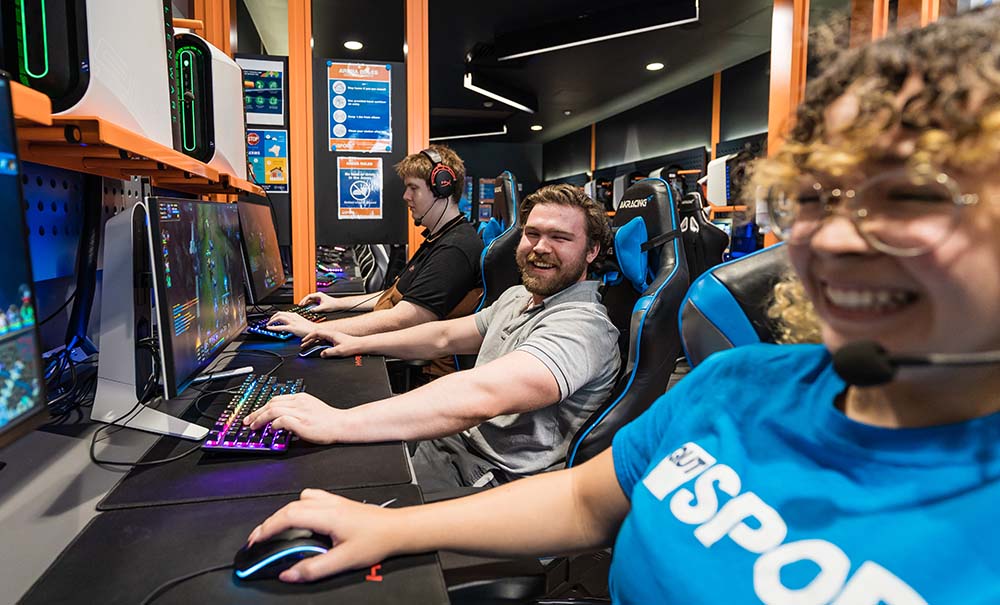 Three players compete alongside each other in the QUT eSports Arena.