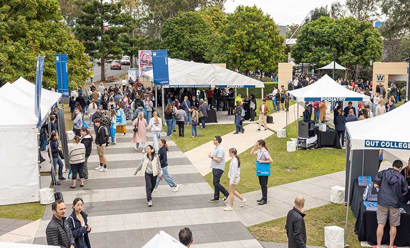 A crowd of people move between multiple tents set up in a courtyard at Kelvin Grove.