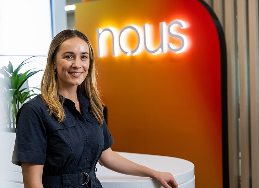 Sally Higgins in front of Nous Group sign