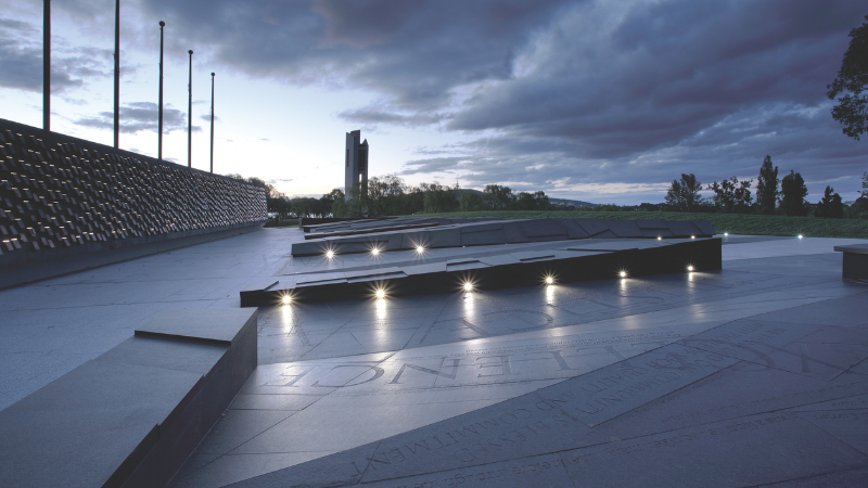 A concrete structure with lights illuminating words etched into the structure.