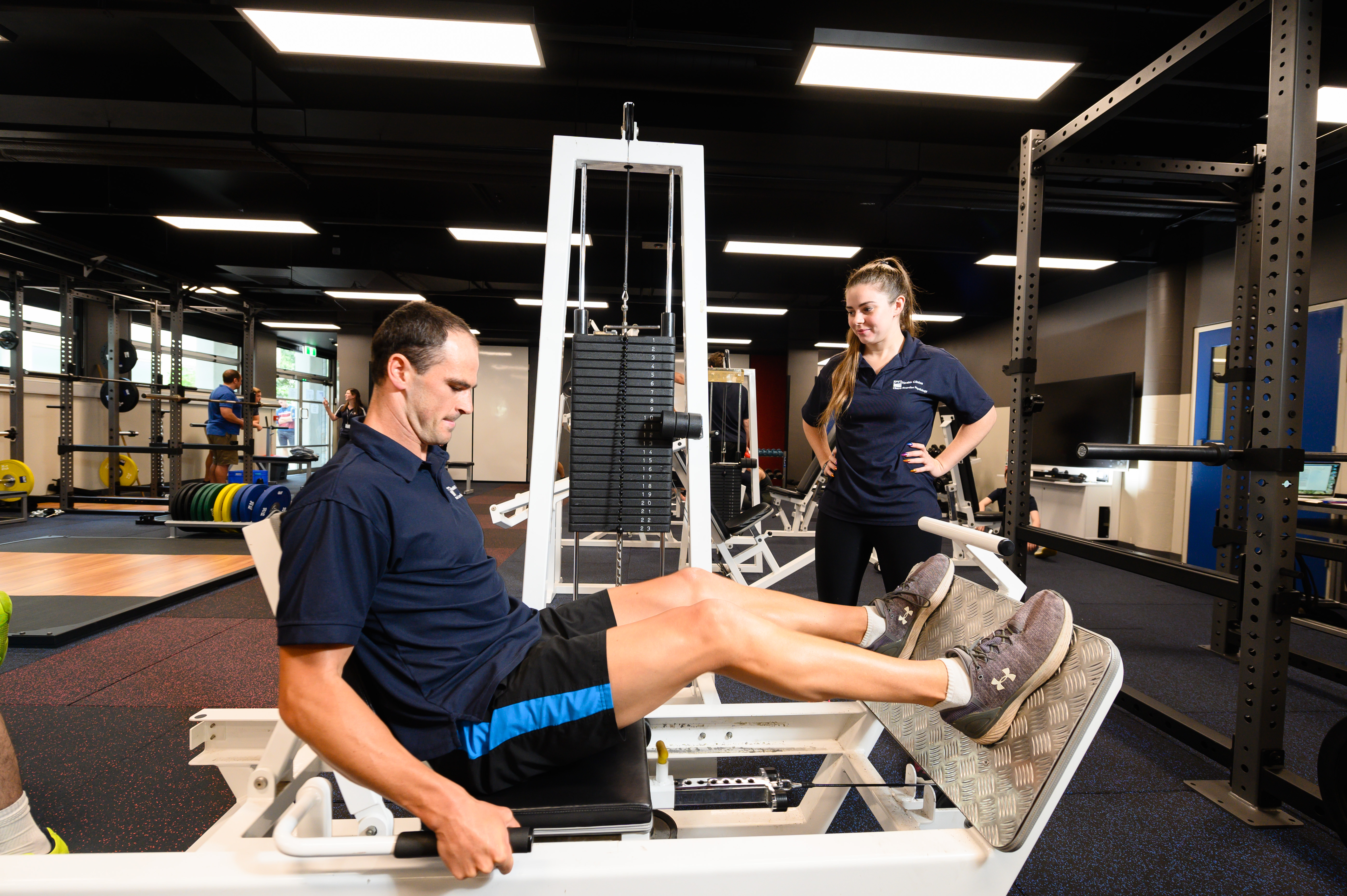 Sport and exercise students in training lab using leg press