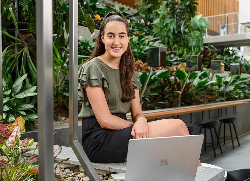 Smiling woman sits in front of a laptop