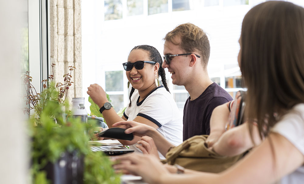 A group of students sit together at the counter of a coffee shop.