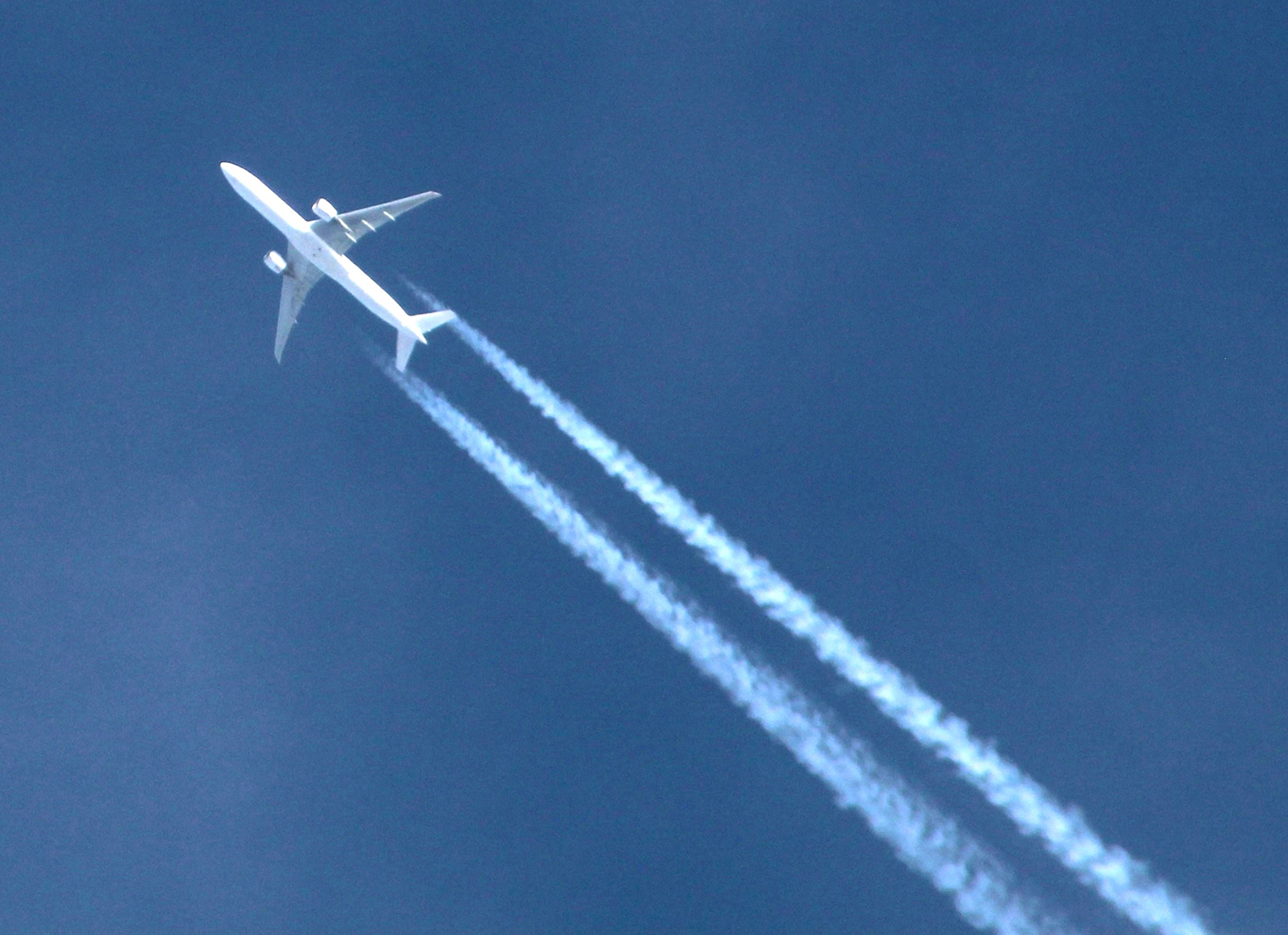 Plane in blue sky with a condensation trail behind it