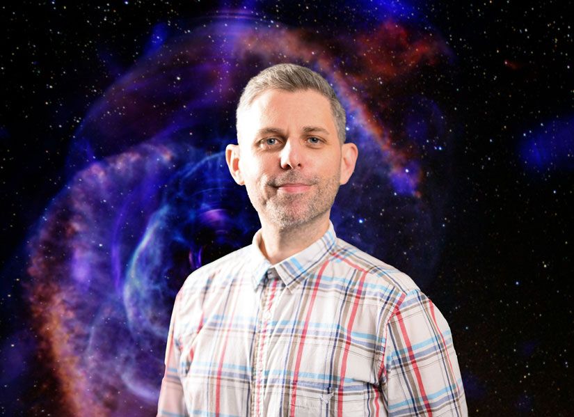 Dr Michael Cowley standing in front of a background showing a Rose-shape nebula in space