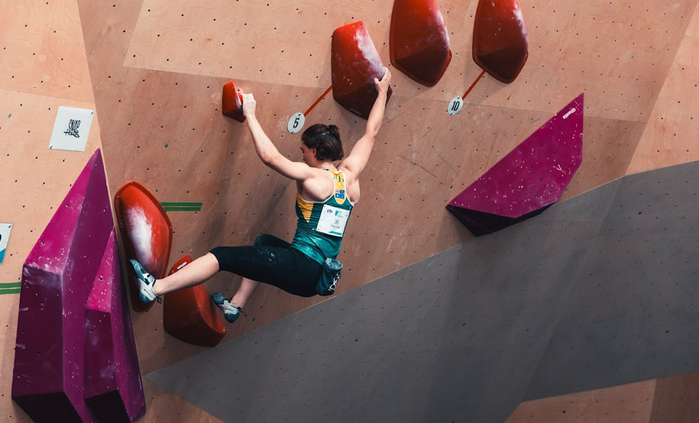 A woman climbs an indoor rock-climbing wall.
