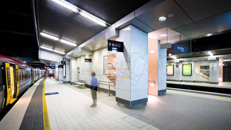 An underground trainstation with clean white glossy walls and a squiggly line artwork shown aross them.