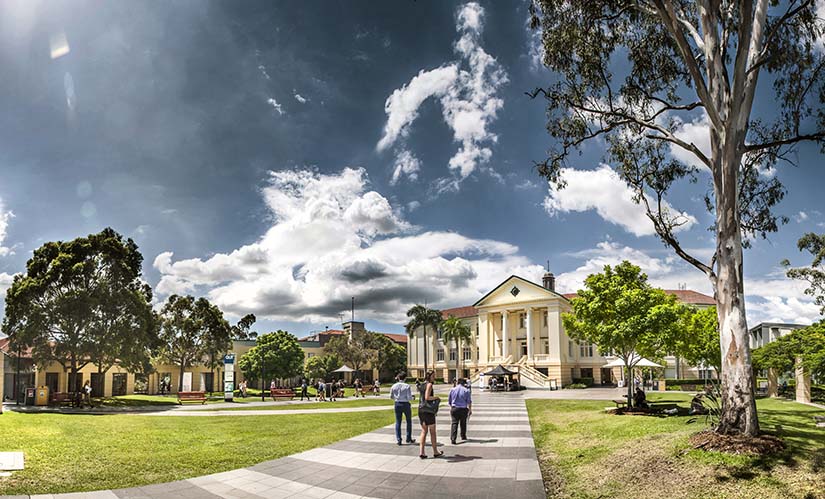 A group of students walk along a pathway towards a university building.