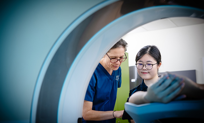 A student and a technician check the settings of an MRI machine.
