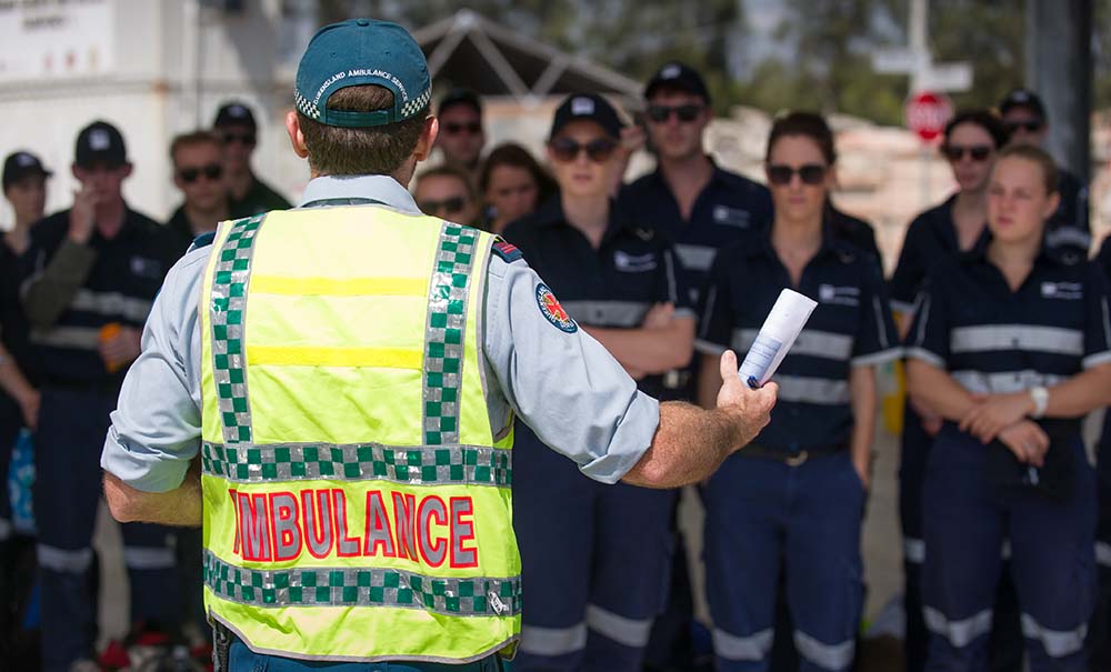 A Queensland Ambulance Service officer briefs a group of QUT students