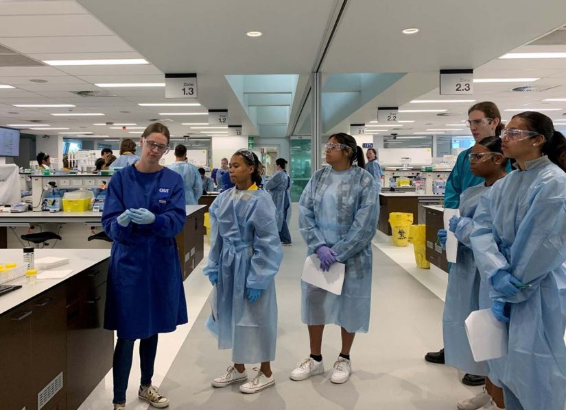 Two Indigenous students work with a laboratory technician to complete an experiment.