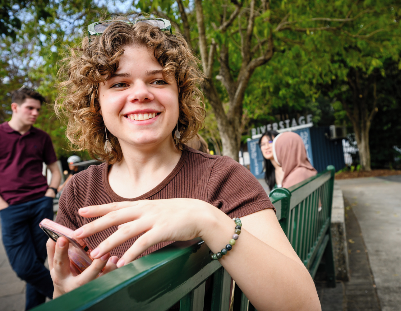 Female student holding cell phone, smiling into the distance
