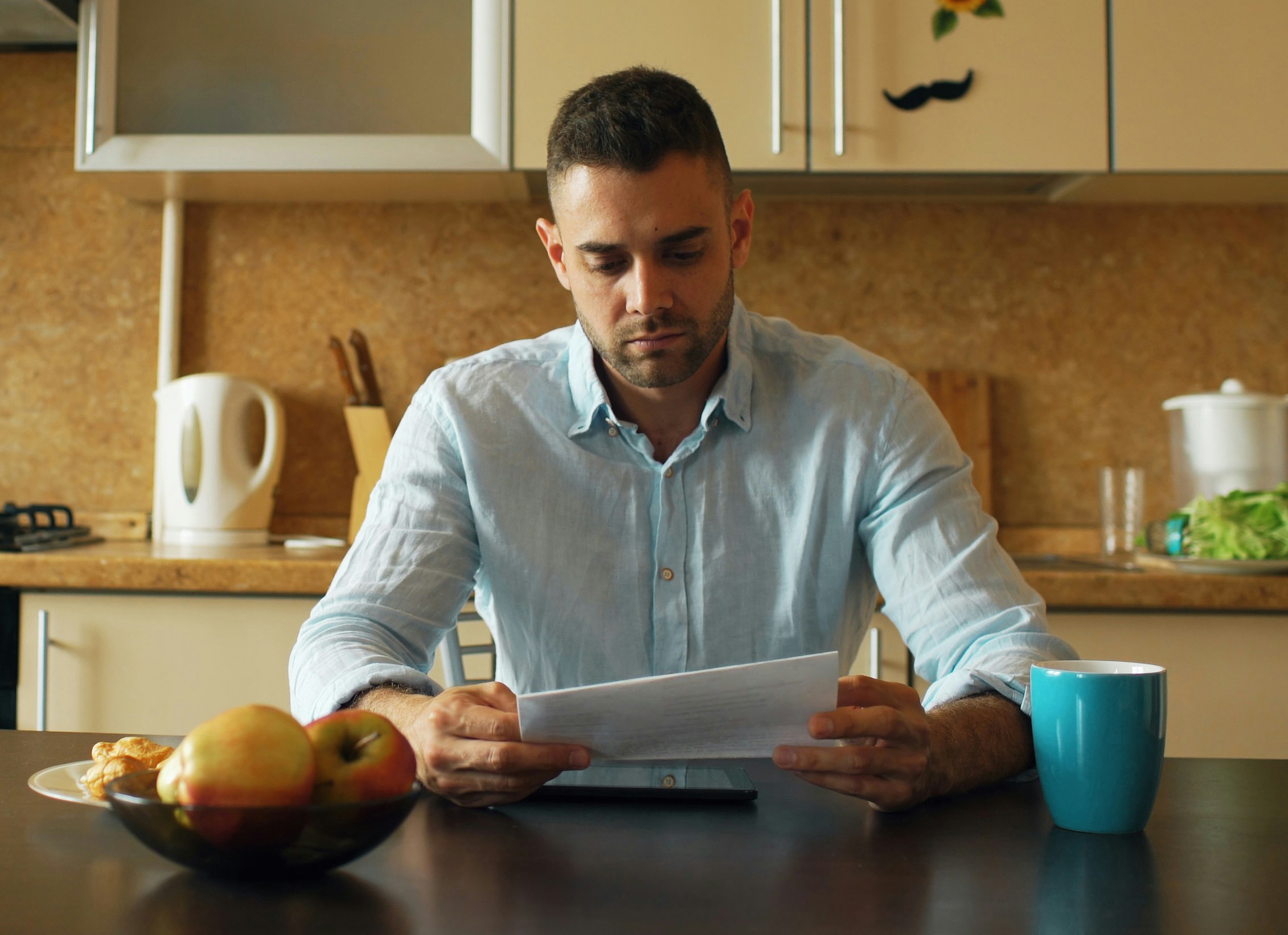 Man with bill sitting in kitchen