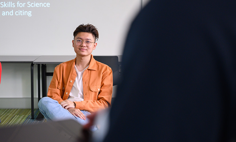 A non-binary student sits and listens in a class.
