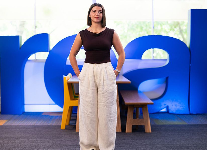 Kitty Murphy Addison standing in front of giant 'REAL' letters