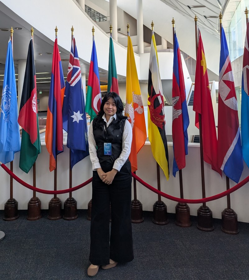 Keisha Nikola standing by various flags at the summit