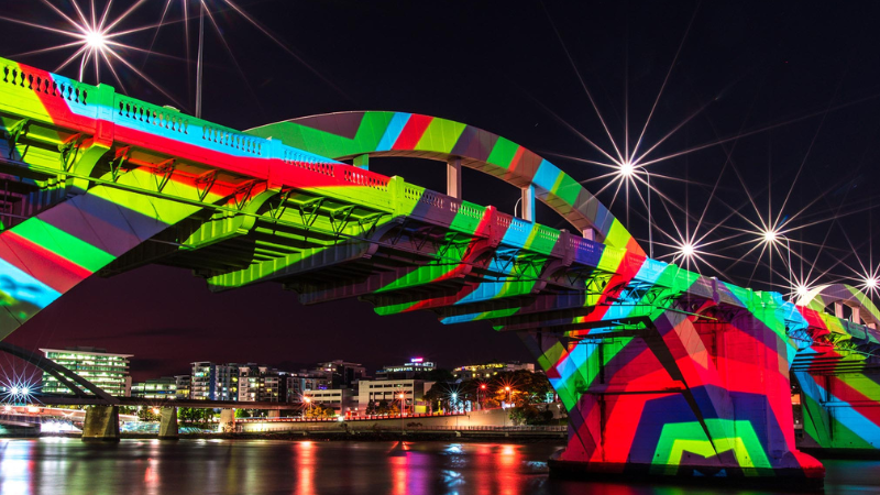 A bridge at night with a colour light projection shown across it.