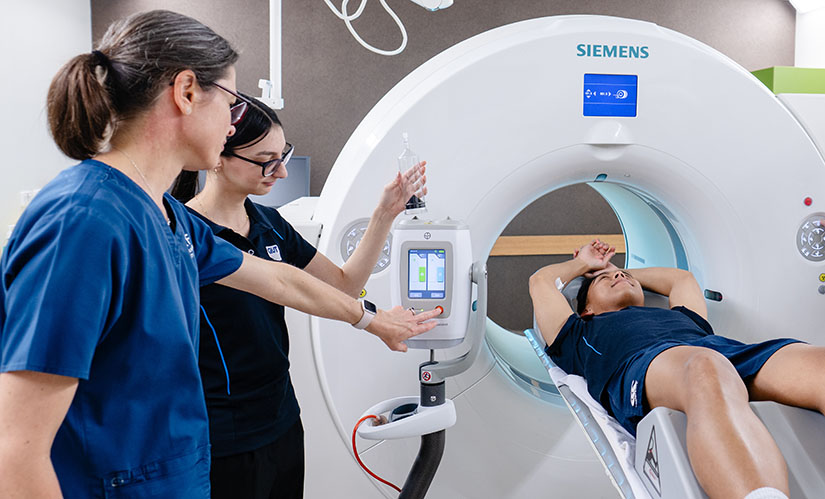 A QUT student and an academic in a training room practice setting up an MRI scan of a patient.