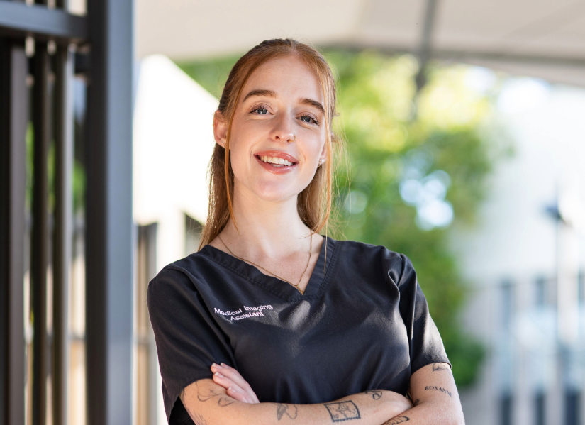 female physics student wearing medical imaging uniform smiling confidently towards the camera