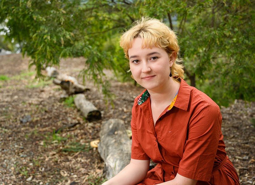 Woman sits outside in front of bushland