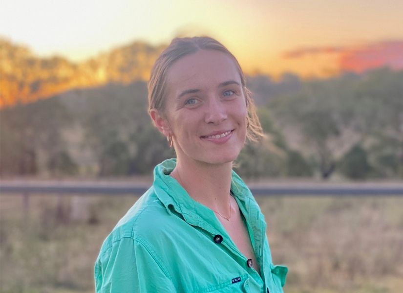 Sally Higgins smiling to camera. Hair tied up. Sunset. 