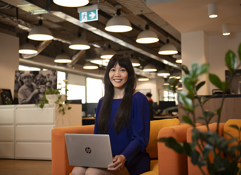 Image of Esther Au sitting in her office with her laptop