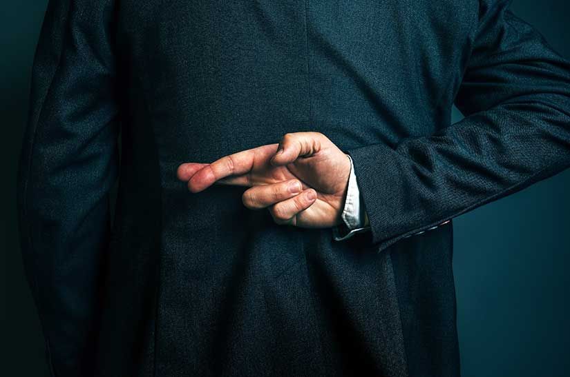 Man in suit crossing fingers behind his back