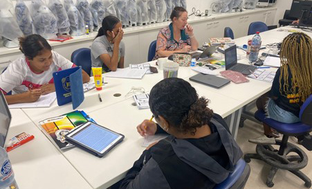 A group of Indigenous high school students sitting at a table participate in a data workshop.