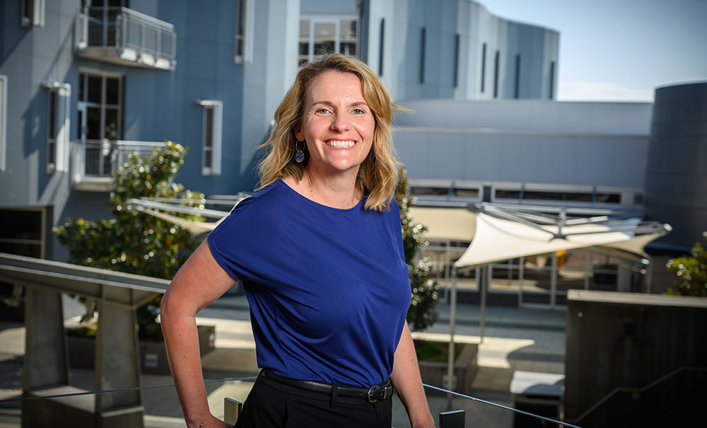 A smiling woman standing on a university campus.