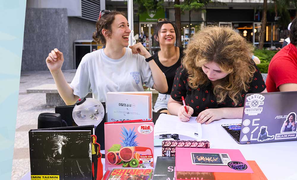 A group of laughing students sign up to join a club.