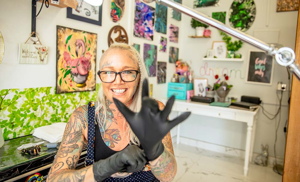 A tattoo artist pulls on gloves before tattooing a client.