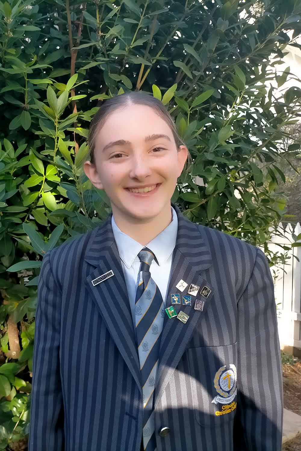 Smiling girl in school uniform stands in her front garden