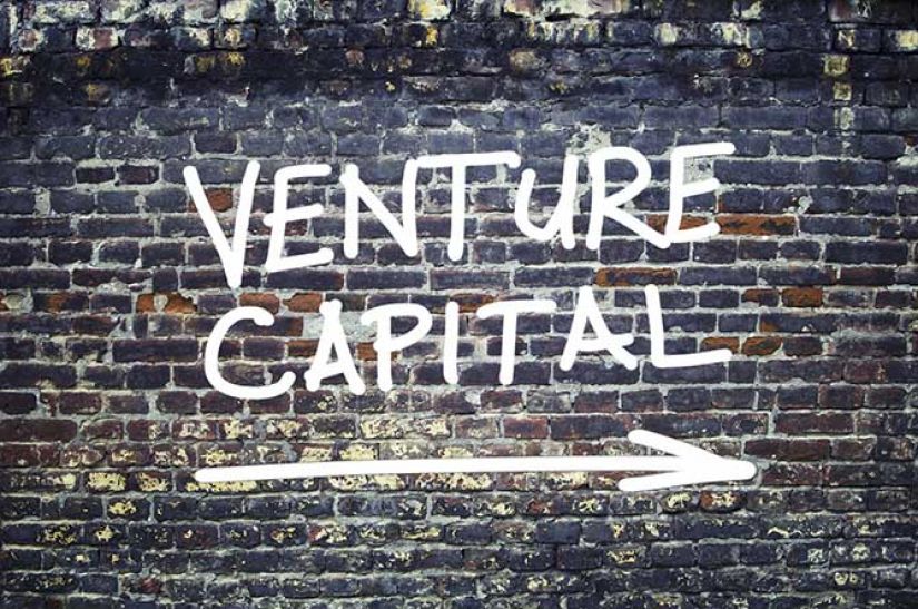 Brick wall with VENTURE CAPITAL spray painted on it