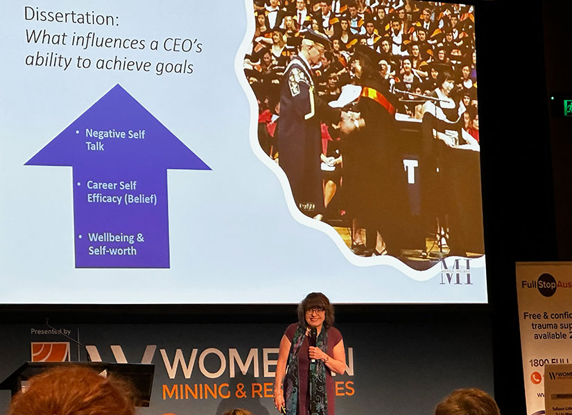 Margie speaking on stage in front of an audience