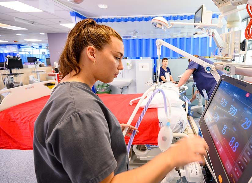 Nurse in intensive care unit checks computer monitor