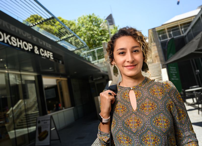 Female postgraduate student standing outside the bookshop on our Gardens Point campus.